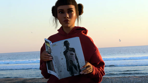 Miquela Sousa wearing a red hoodie while reading a magazine