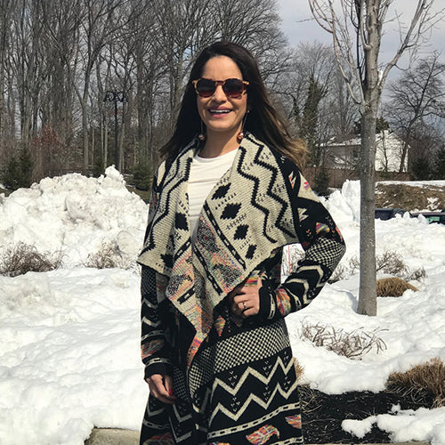 woman wearing a long aztec jacket with white top