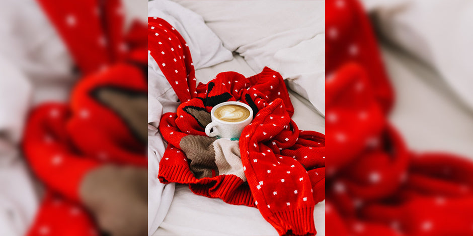 A cup of a coffee placed between red sweater with white spots