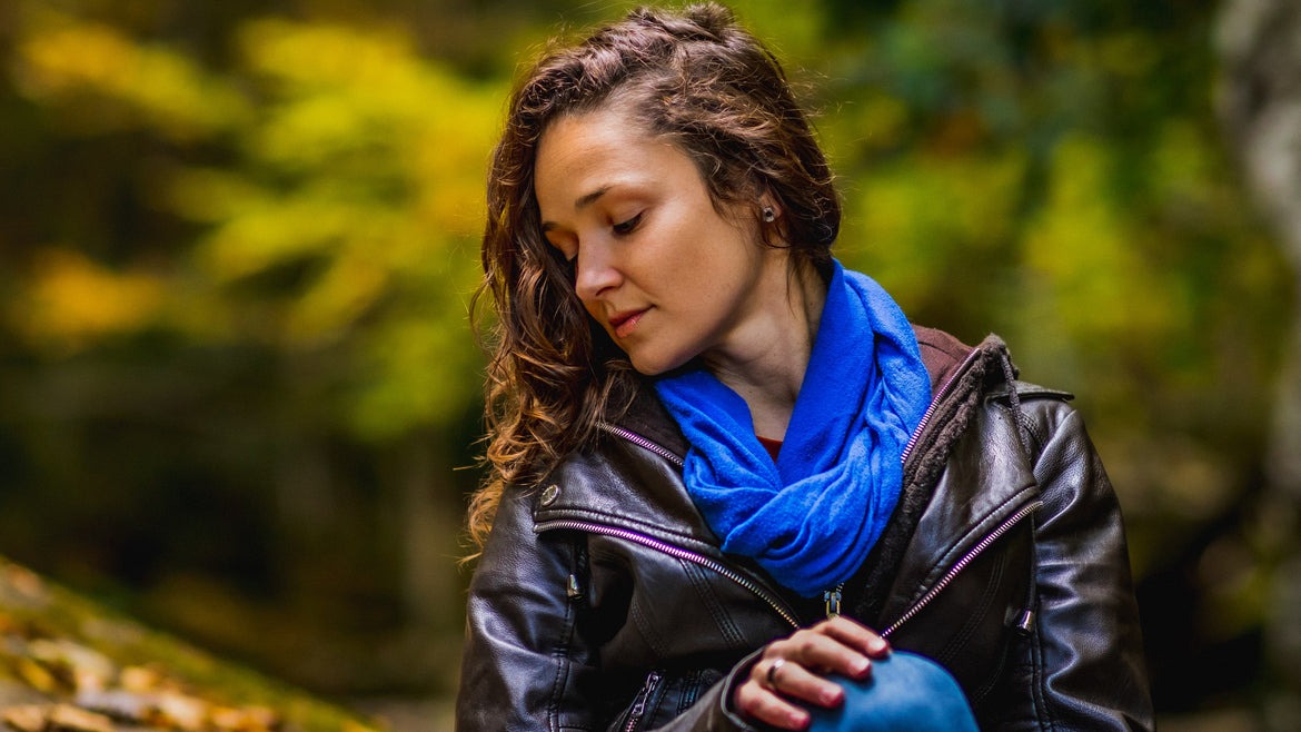 a woman in a blue jacket is holding a blue bag