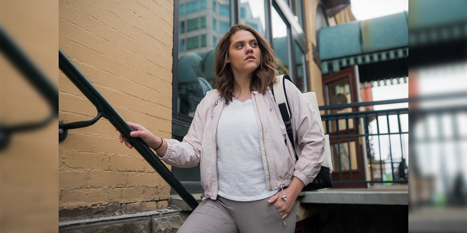 a woman standing in front of a building holding a skateboard