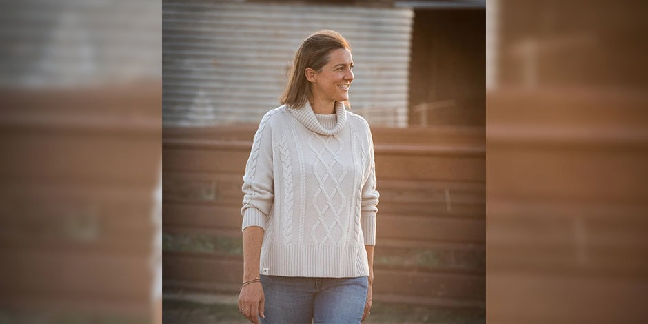 araffe woman in a white sweater and jeans walking down a street