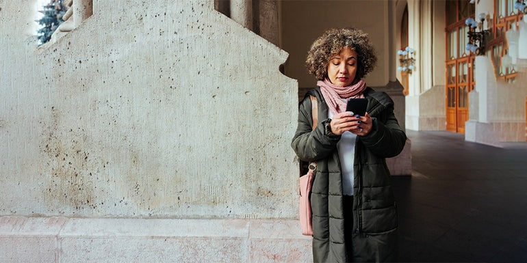 there is a woman standing outside using her cell phone