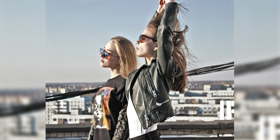 two women holding up their cell phones while standing on a pier