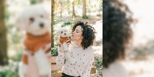 women wearing a white dotted sweater, holding a white dog wearing brown sweater