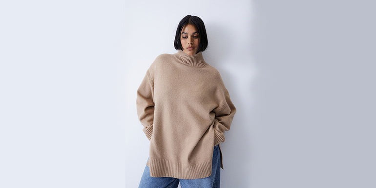 women wearing biege sweater infront of a white wall