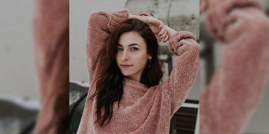 women wearing biege sweater infront of a white wall