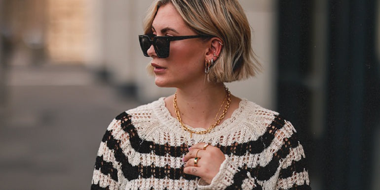 women wearing black and white sweater with a golden chain in her neck