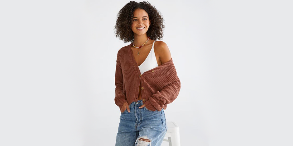 women wearing brown buttonned sweater with jeans sitting on a chair