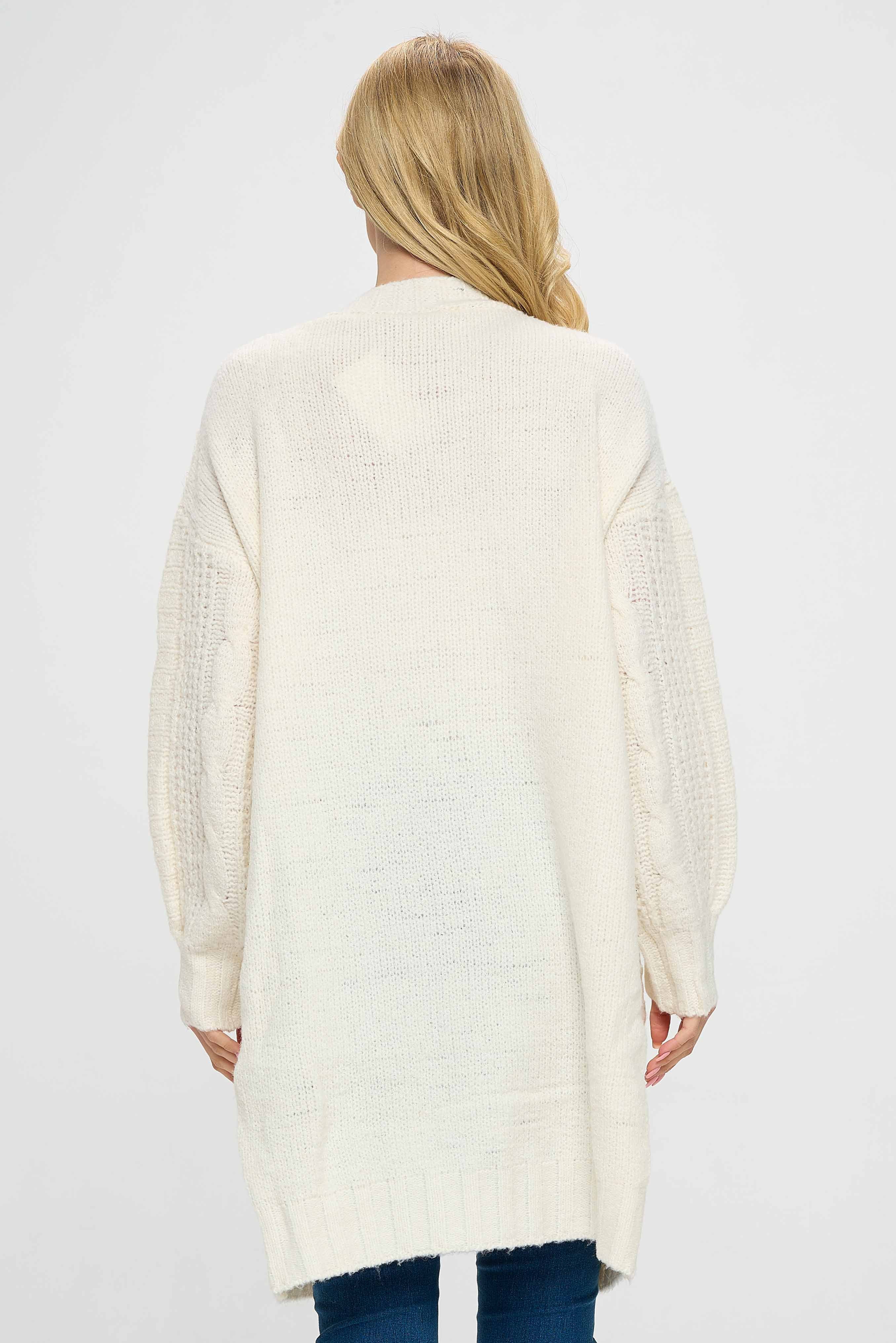 The sweater is perfect for layering over a simple t-shirt or tank top, making it an essential addition to any wardrobe. It can be dressed up or down, making it perfect for a variety of occasions. Overall, our cabled sweater jacket with charming pockets, front open and long in length, is a stylish and comfortable piece of clothing that is perfect for keeping you cozy and stylish during the colder weather.